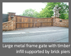 Automatic, electric hinged gate - Large metal frame gate with timber infill supported by brick piers